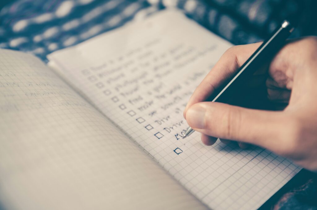 Image by Glenn Carstens-Peters of a notebook with a hand writing out a tasks to delegate list.
